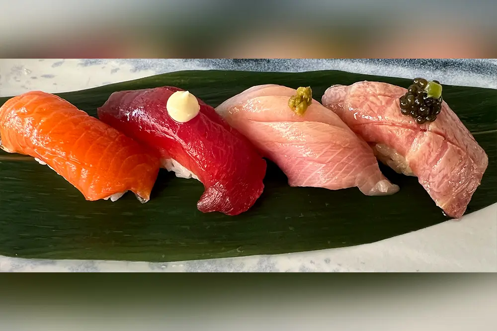 Assorted premium nigiri sushi on fresh green leaf