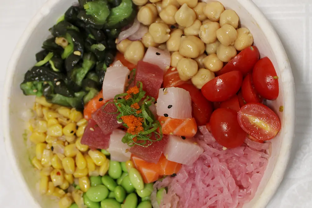 Colorful seafood poke bowl with mixed veggies and fish roe