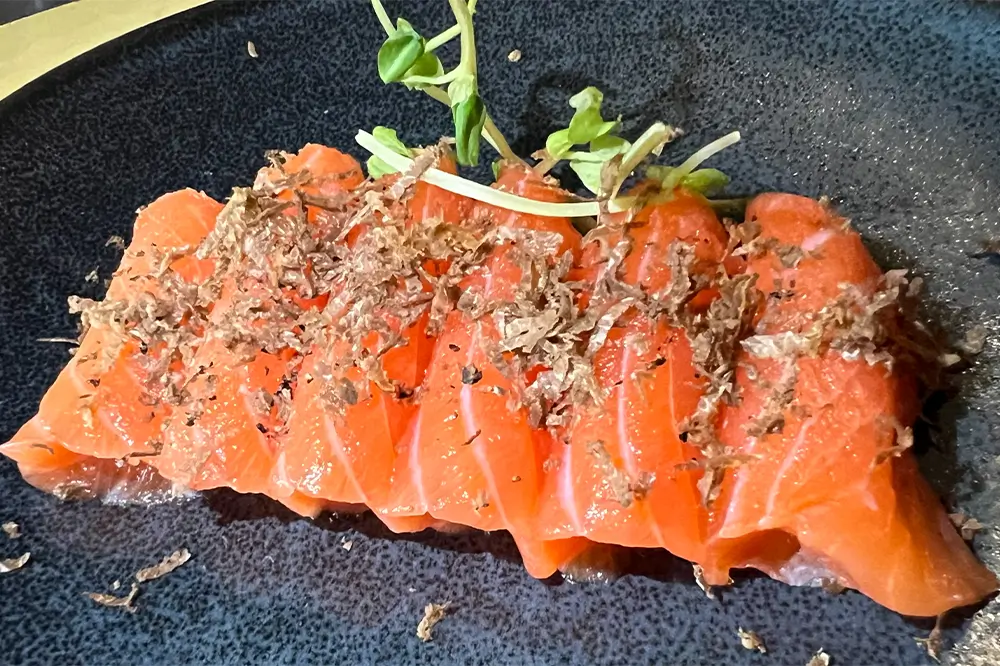 Fresh salmon sashimi garnished with truffle shavings and sprouts