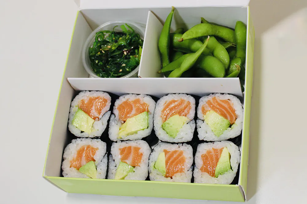 Salmon avocado maki roll bento with edamame and seaweed salad
