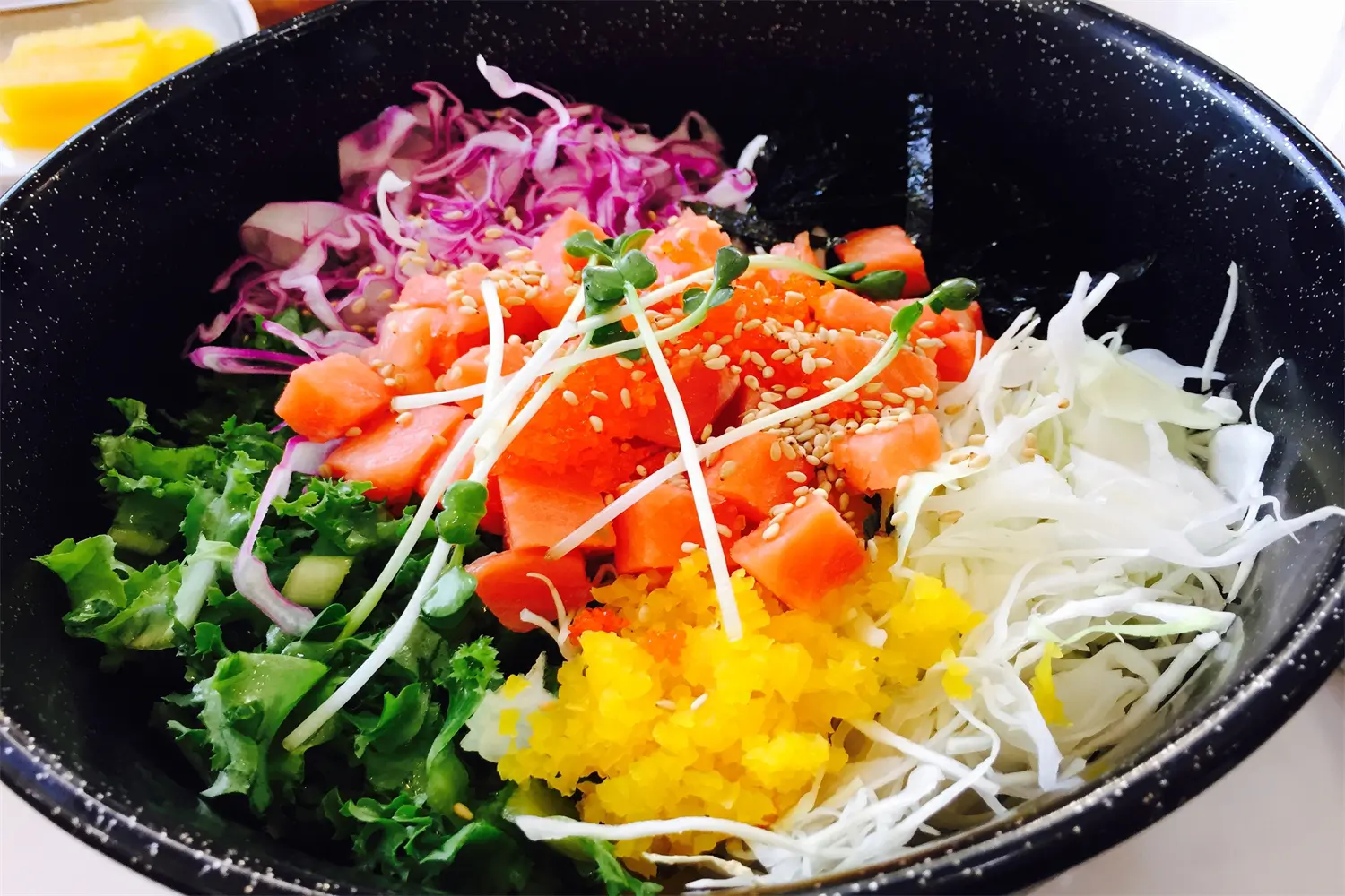 Salmon poke bowl with vegetables, fish roe and sesame seeds